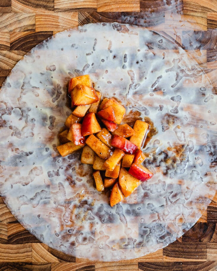 Sautéed apple filling spooned in a line across a softened rice paper wrapper