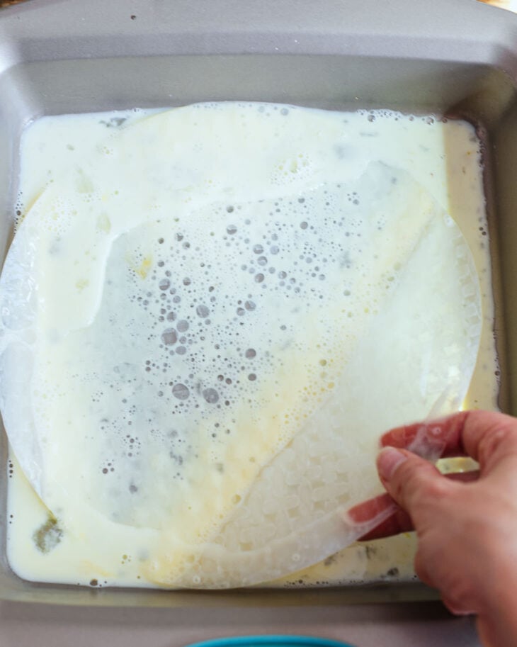Rice paper wrapper soaking in a milk and egg mixture in a shallow dish