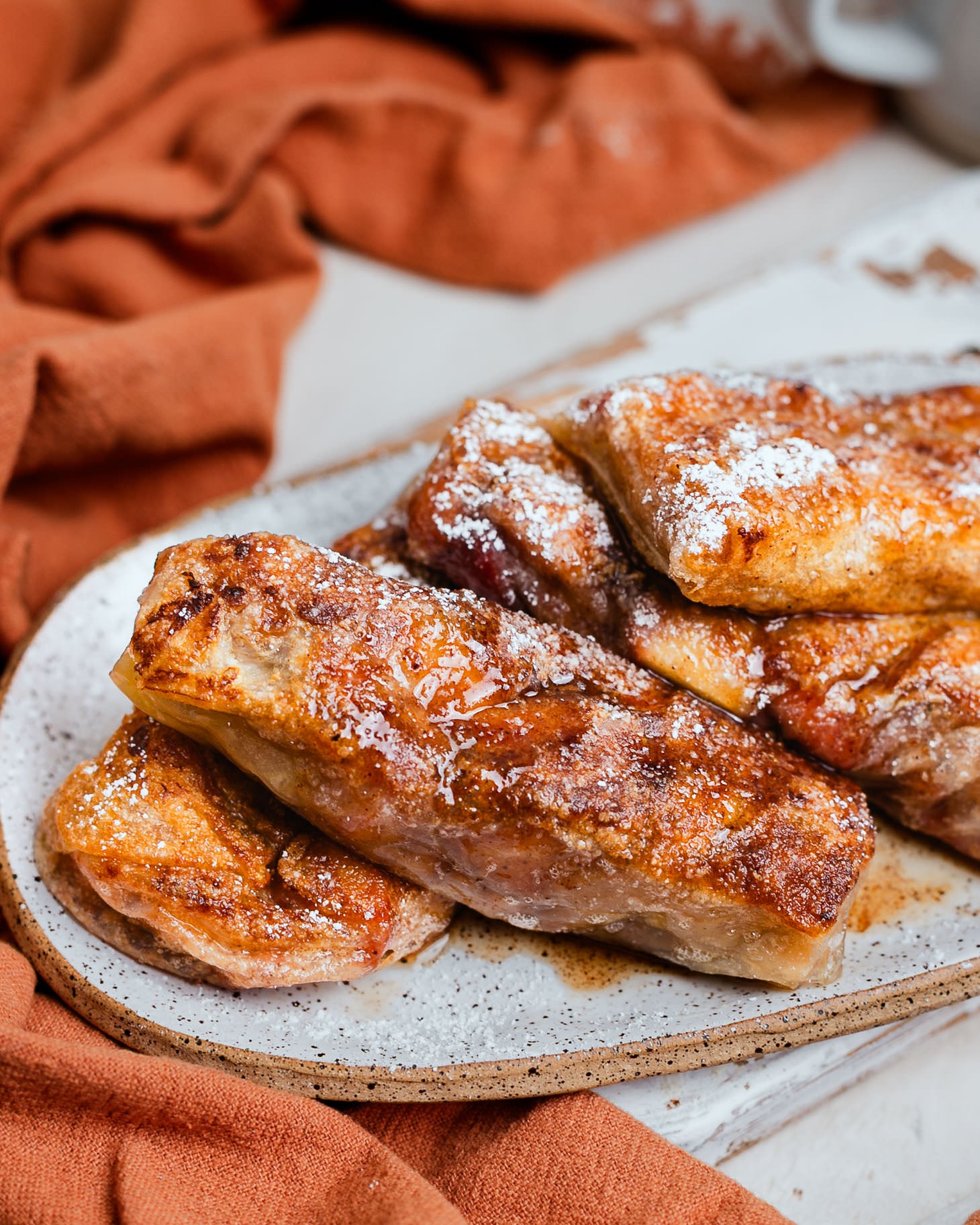 Warm apple pie spring rolls served with powdered sugar and caramel sauce