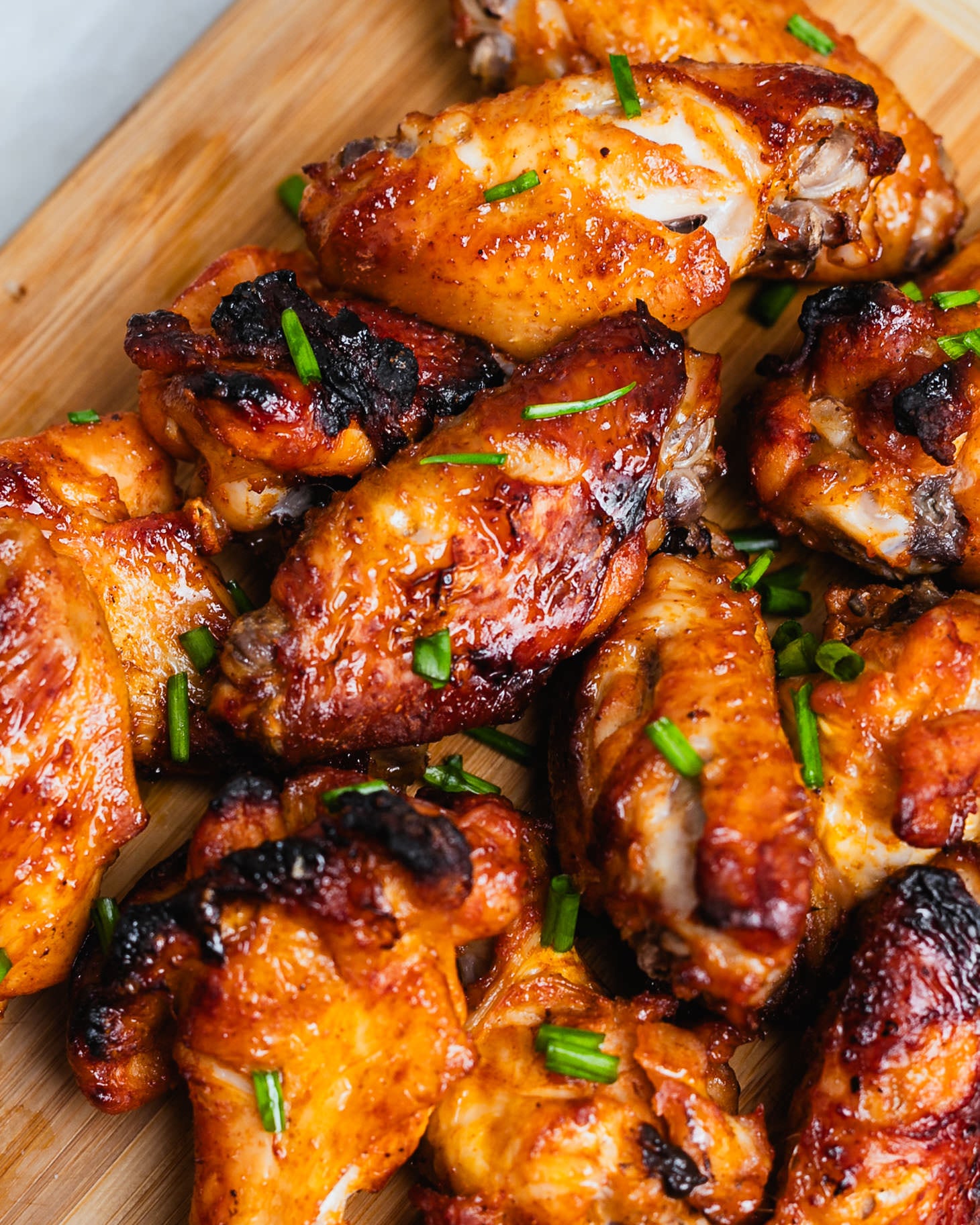 Close up of caramelized honey soy chicken wings with green onions