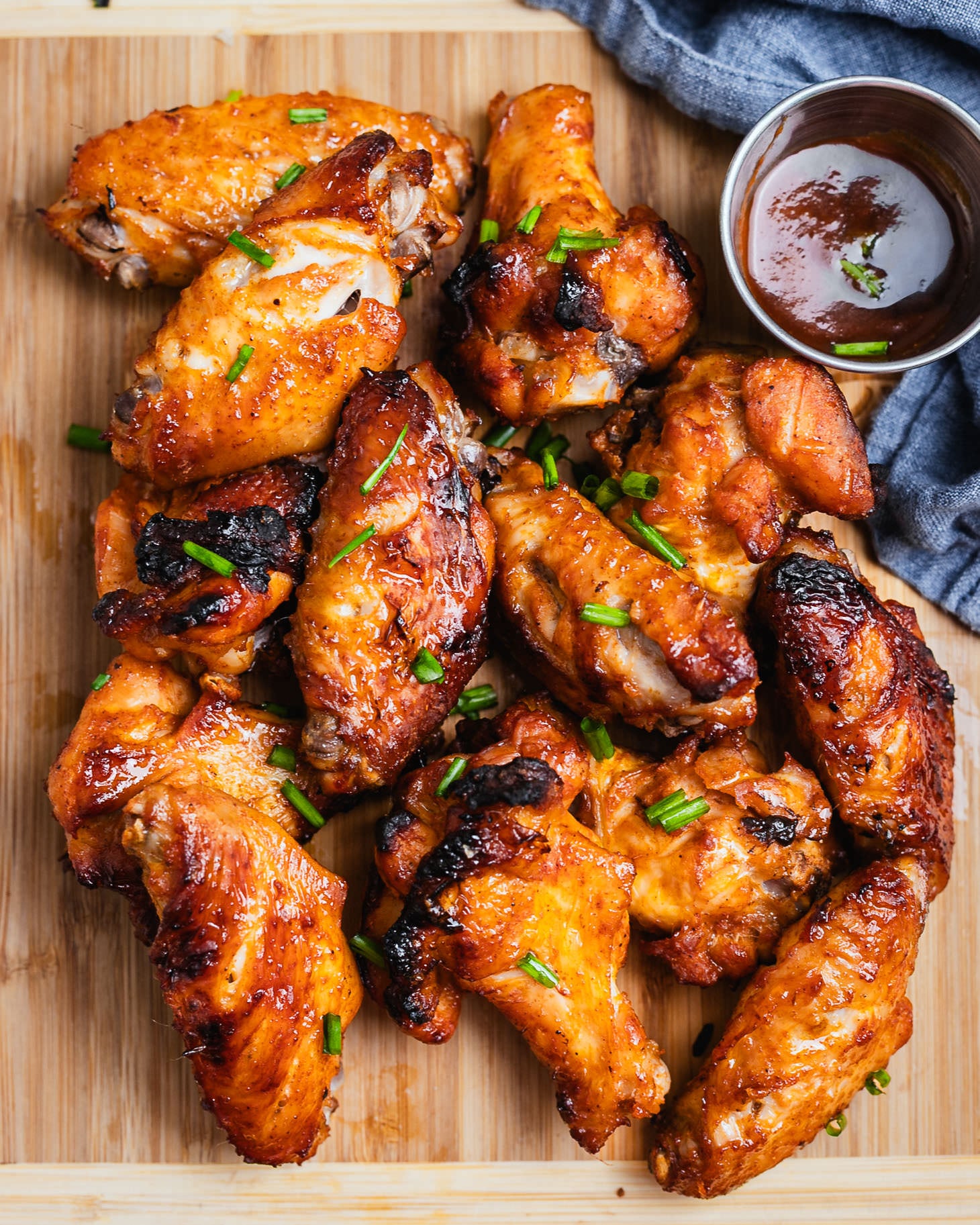 Crispy honey soy chicken wings garnished with green onions on a wooden board