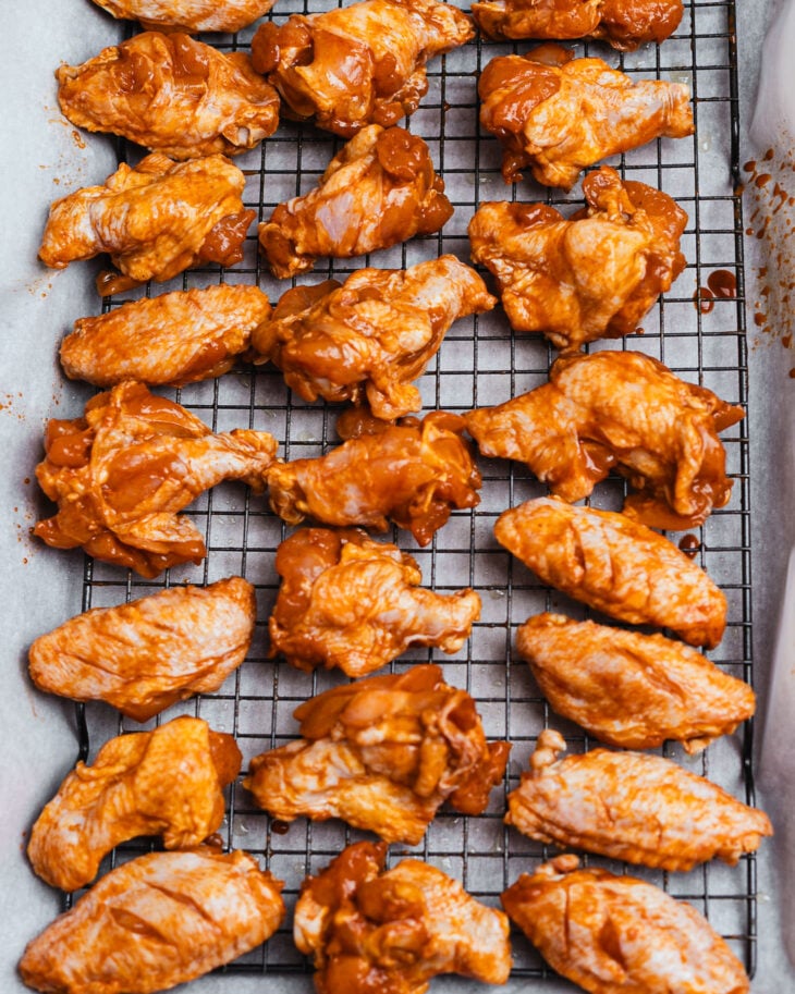 Marinated chicken wings arranged on a wire rack over a sheet pan
