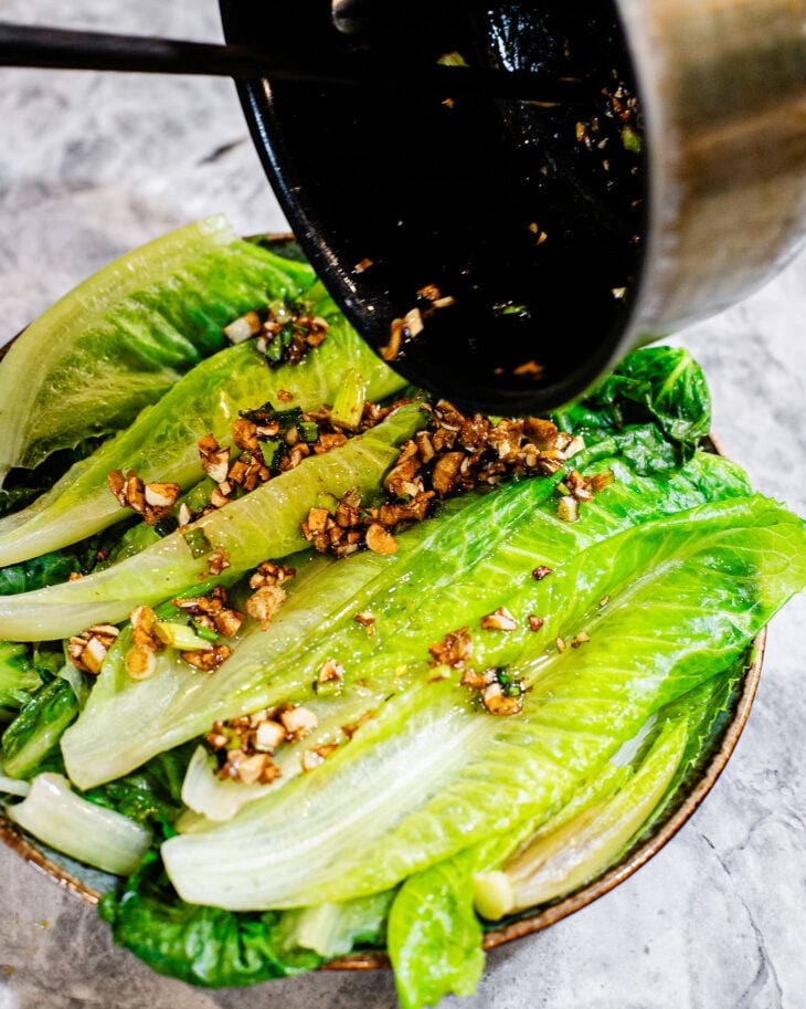 Pouring hot garlic sauce over blanched lettuce