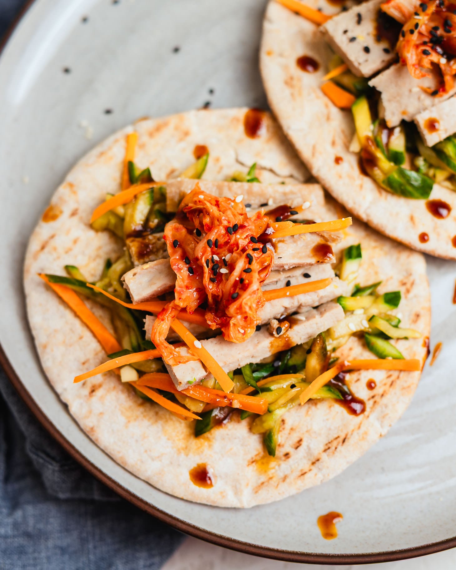 Sheet pan dumpling wraps on flour tortillas with carrots, cucumber, and kimchi